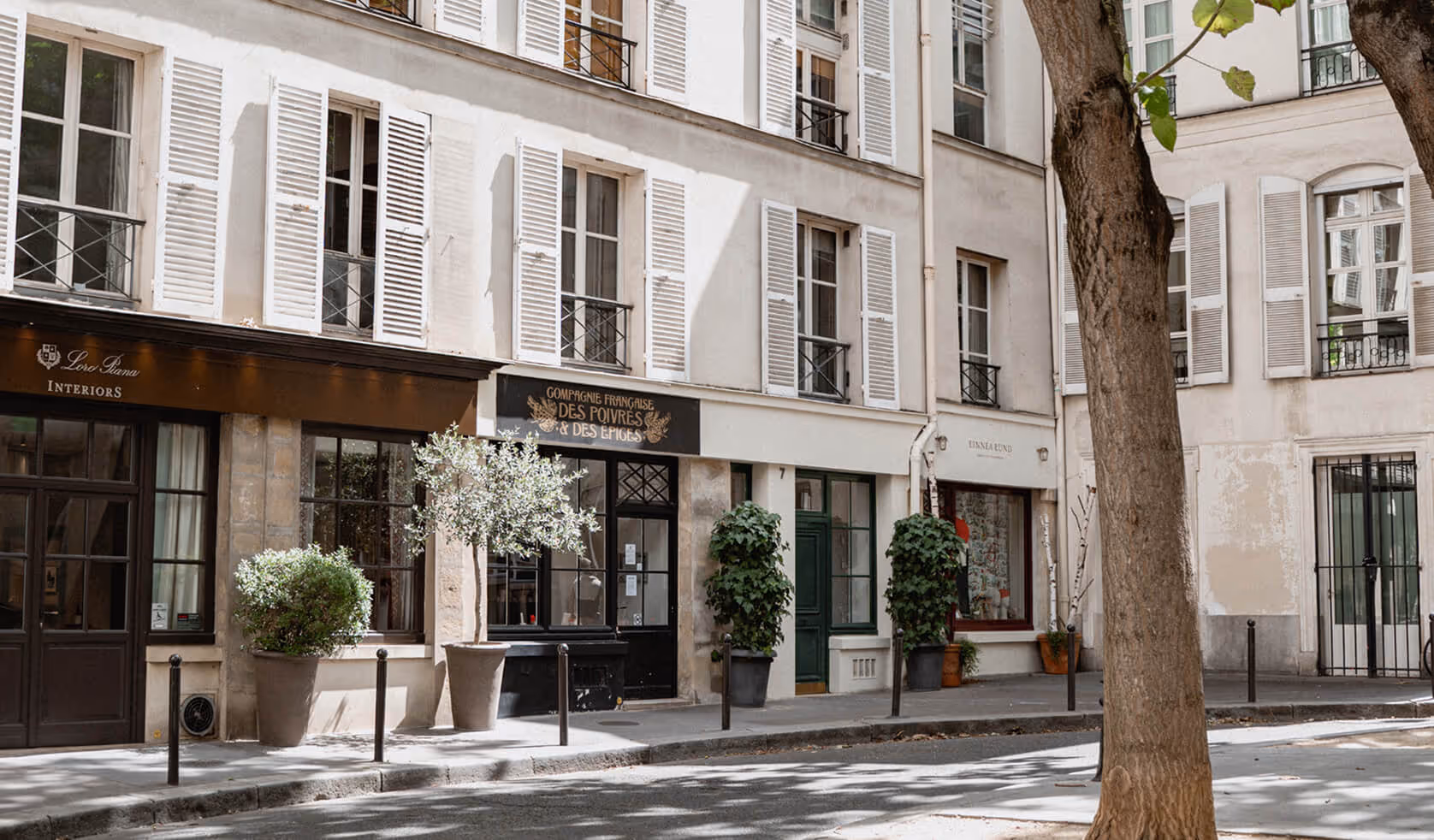 Façades de bâtiments avec fenêtres à volets blancs et boutiques en rez-de-chaussée, dont une avec enseigne noire et or 'Compagnie Française des Poivres & des Épices'.- Hôtel Madison