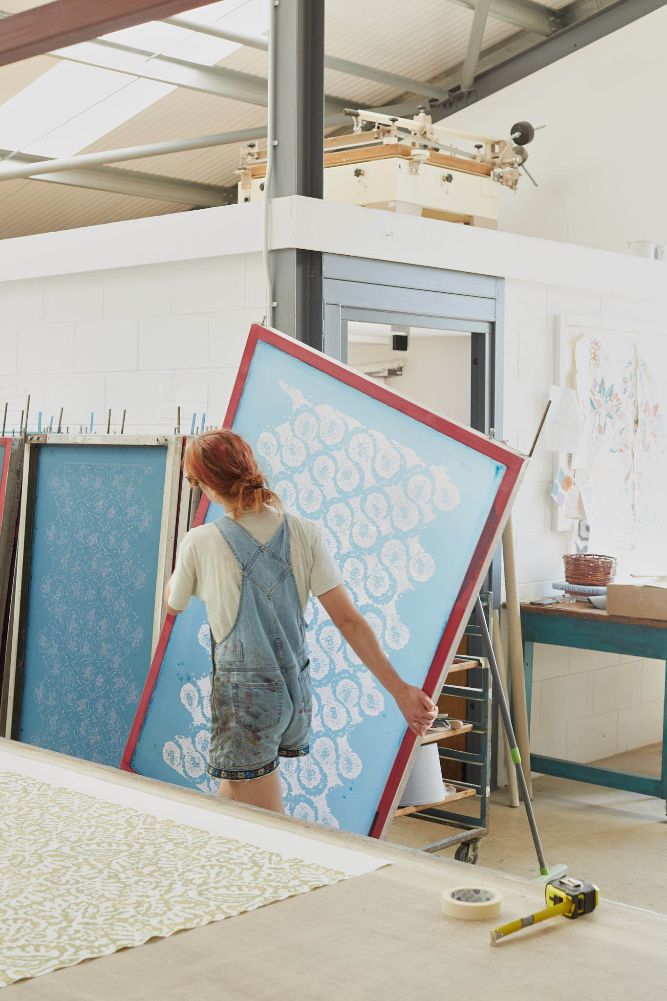 Rapture and Wright woman carrying large blue silk screen through factory