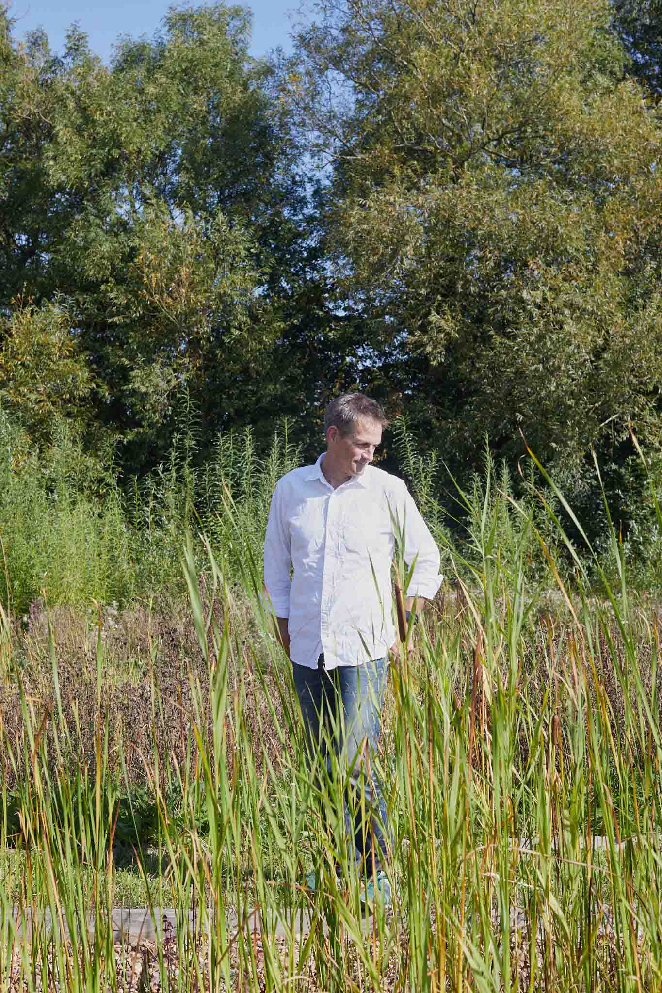 Rapture and Wright man outside walking through tall grasses and surrounded by trees