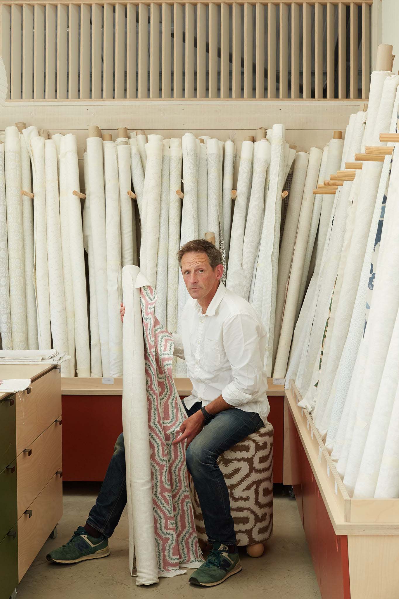 Rapture and Wright man sitting at table surrounded by rolls of fabric
