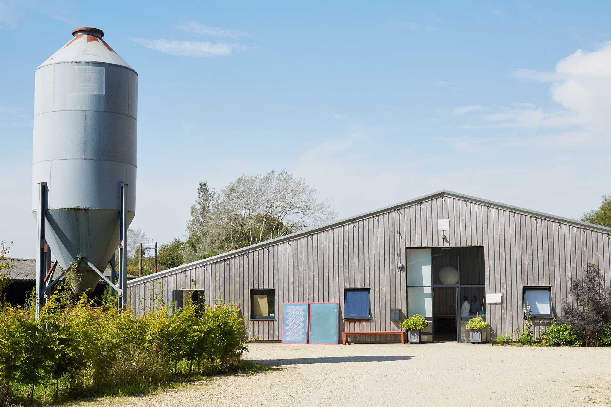 Rapture and Wright outside of factory building blue skies silo to the left