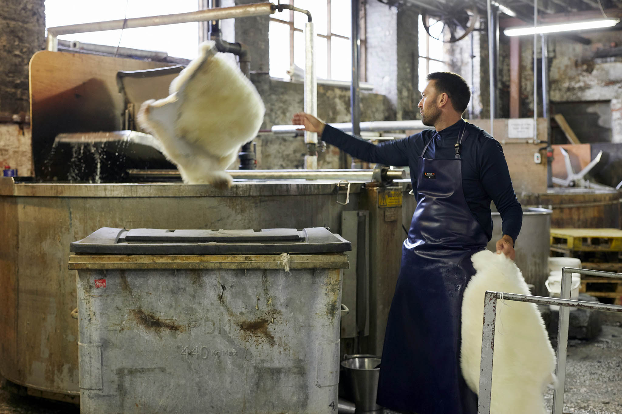 man working with sheepskins in factory devonia