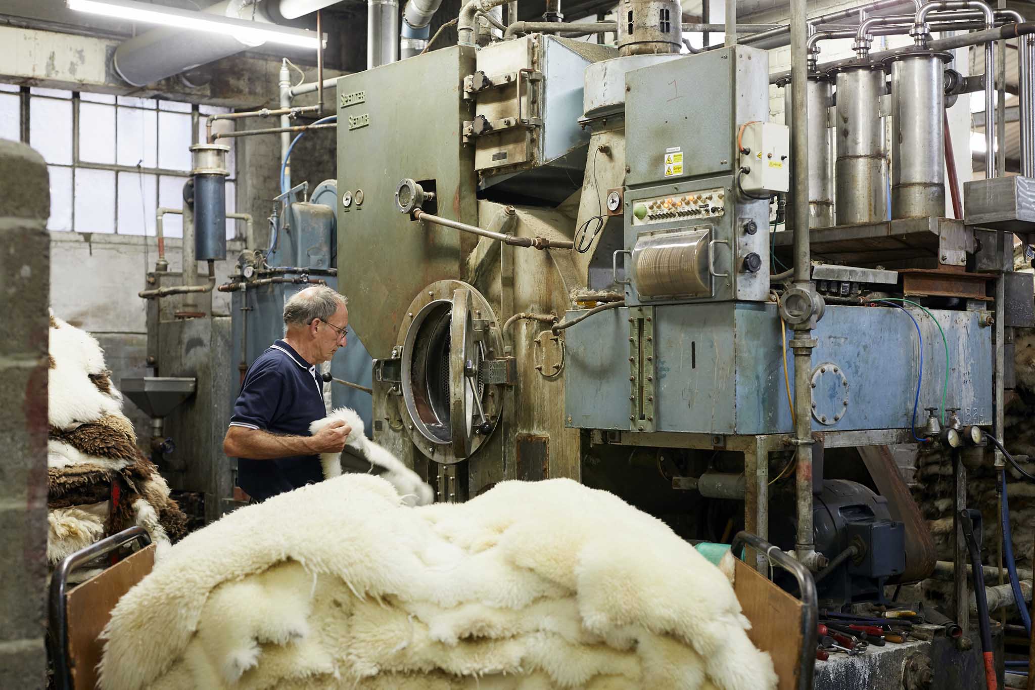 devonia factory worker behind large pile of white sheepskins