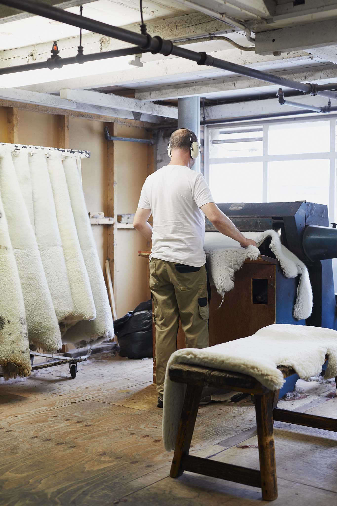 man in room at factory surrounded by sheepskins devonia