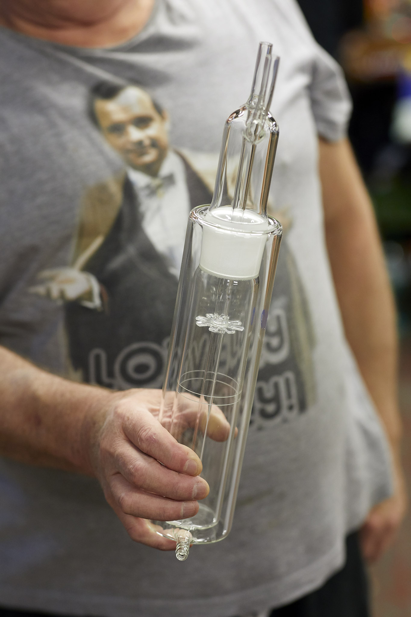 Aimer Products employee in grey t shirt holding large clear glass tube 
