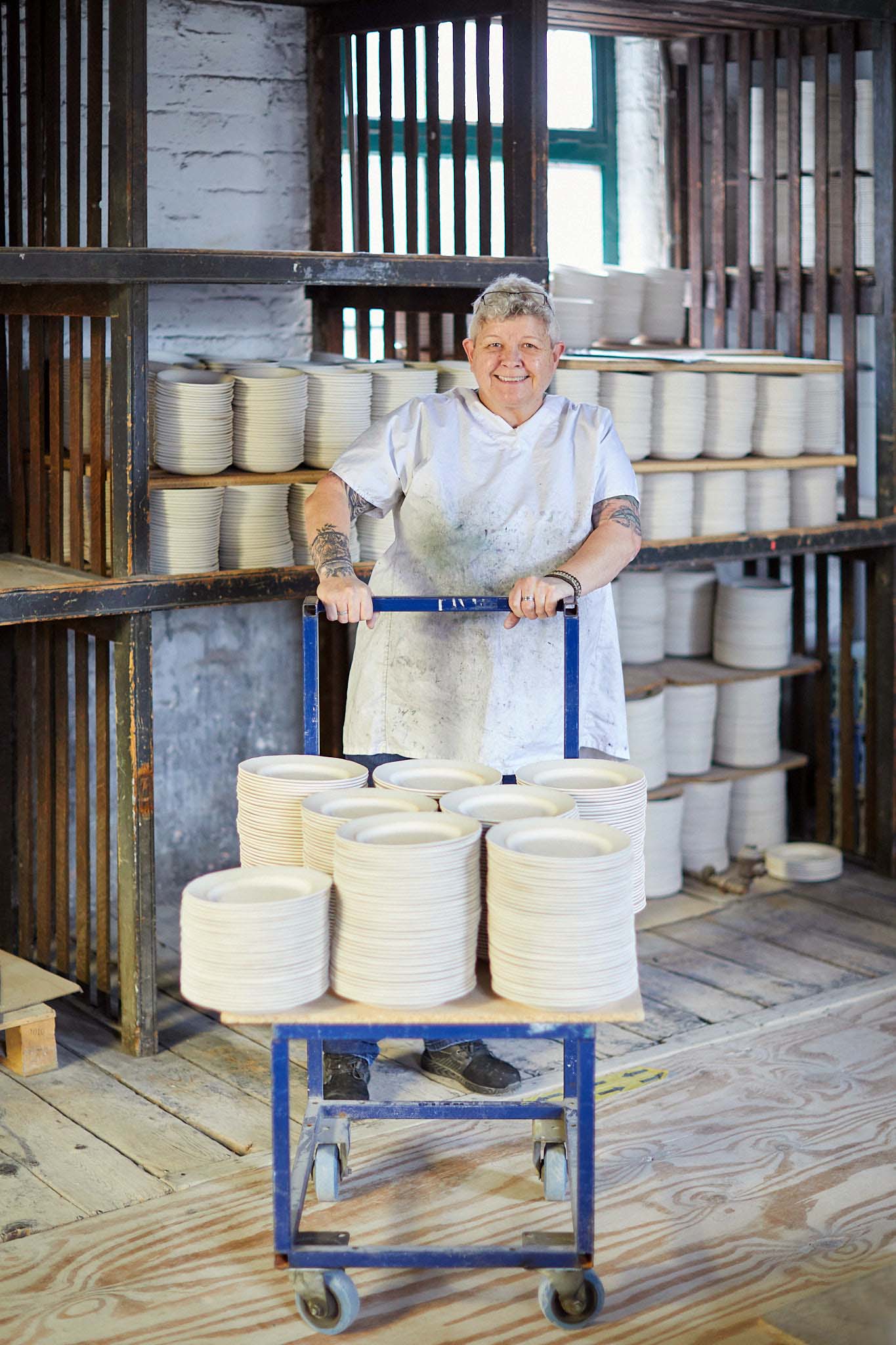Burleigh pottery female factory worker in white pushing trolley of pottery items
