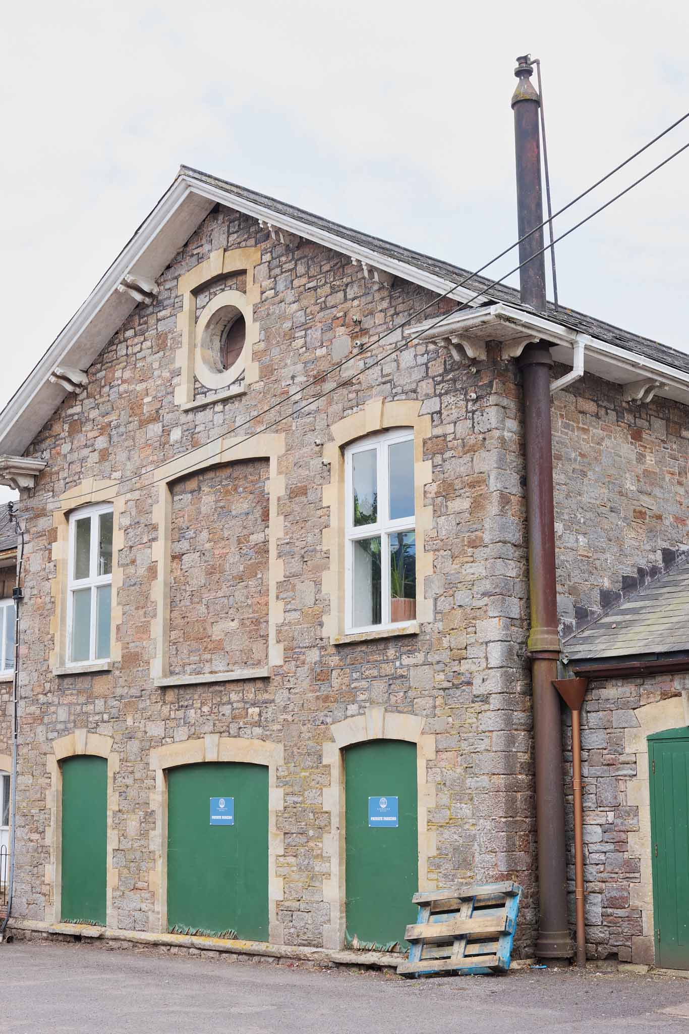 Fox Brothers stone building grey with three bright green wooden door