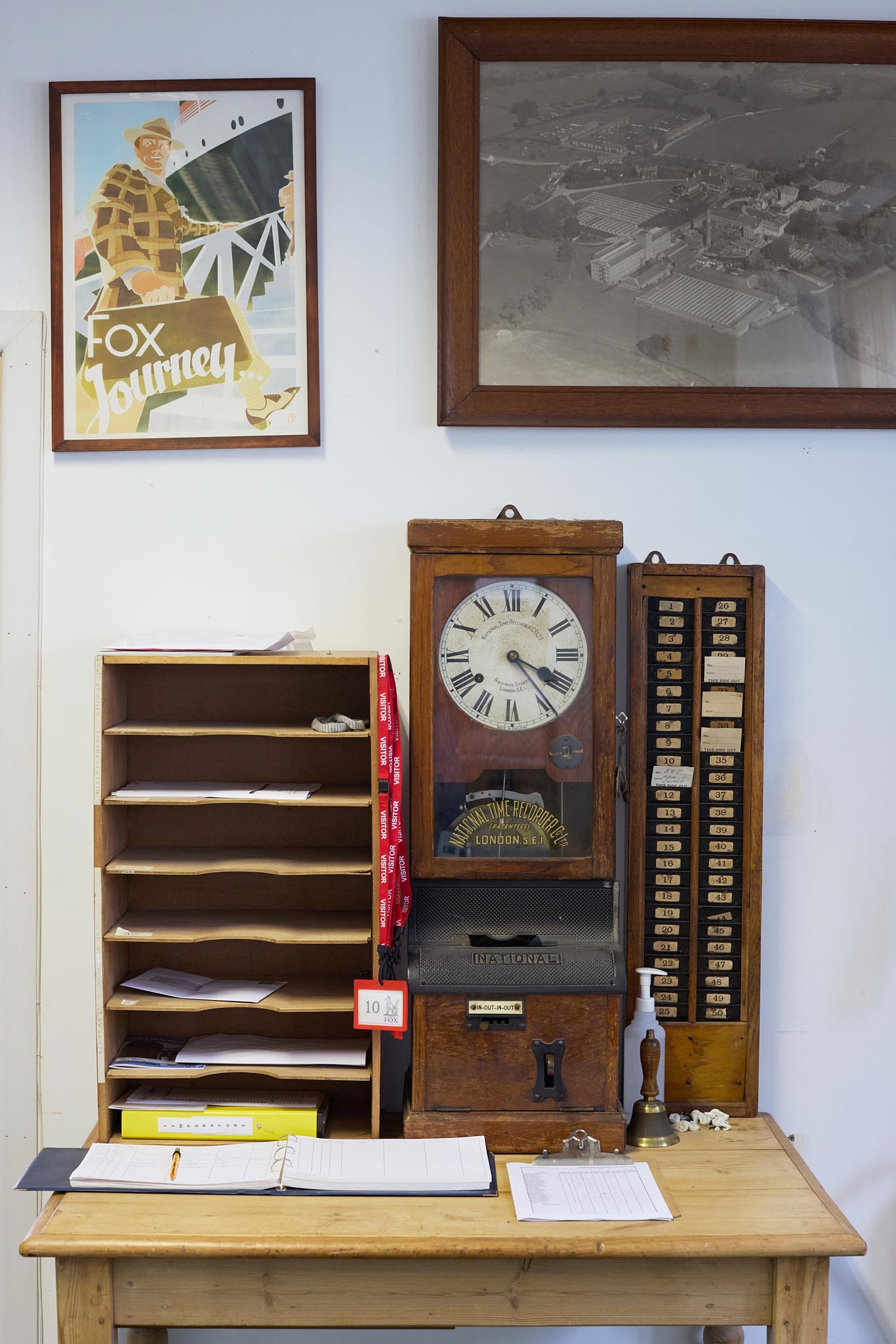 Fox brothers desk in office with old fashioned wooden clock and shelving above the desk are two framed pictures