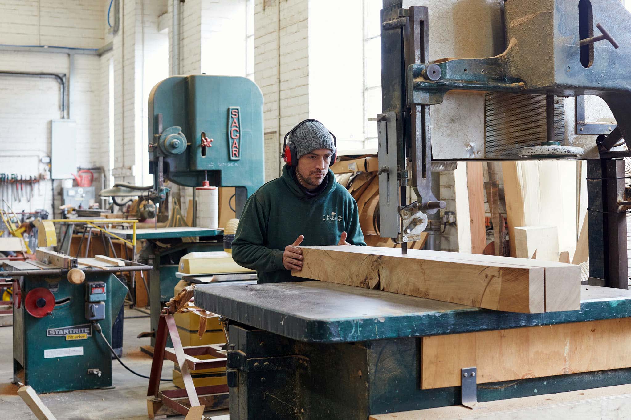 T Nielsen and Co man of factory floor working with large piece of timber 