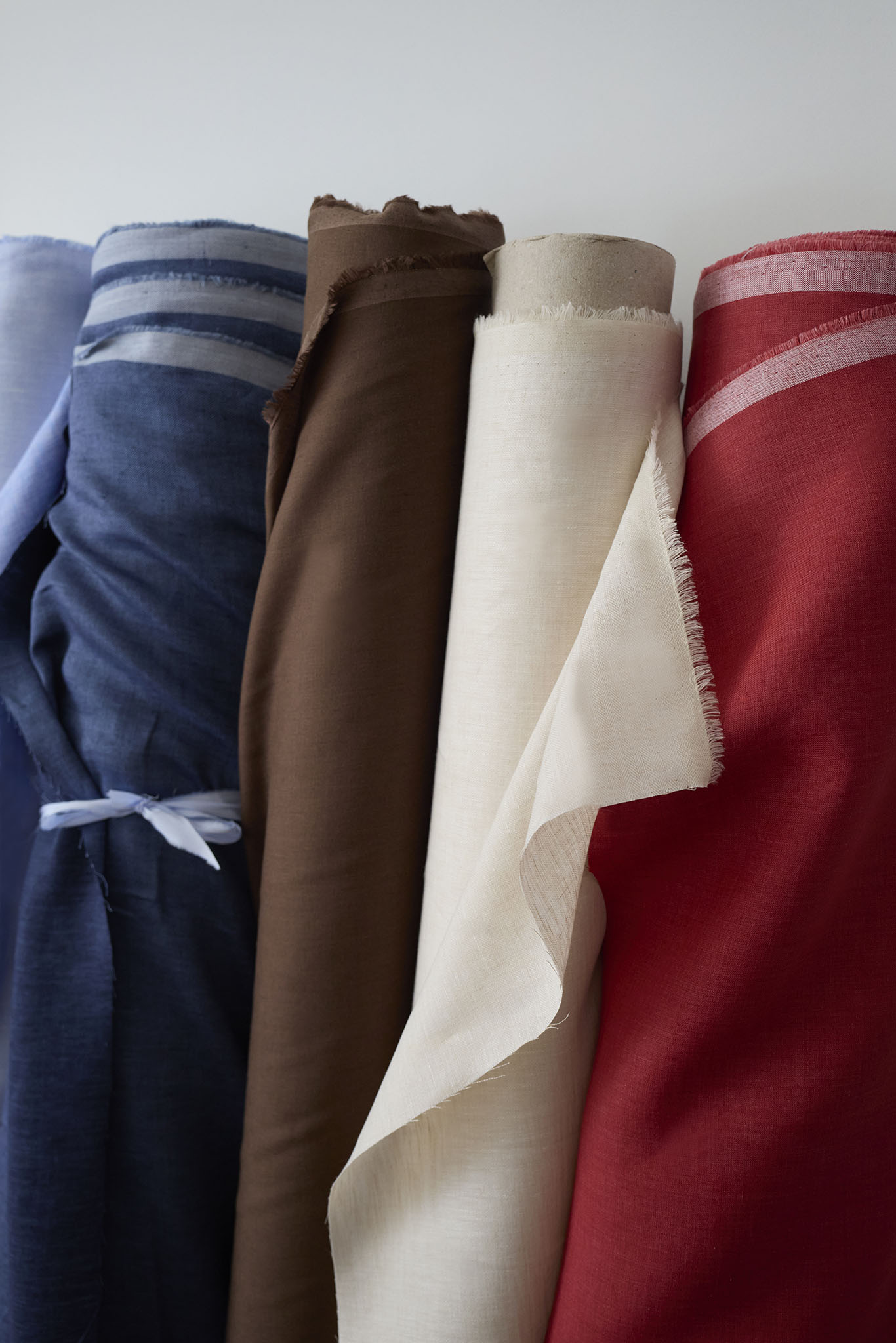  Emma Willis bespoke tailoring rolls of colured fabric leaning against white wall