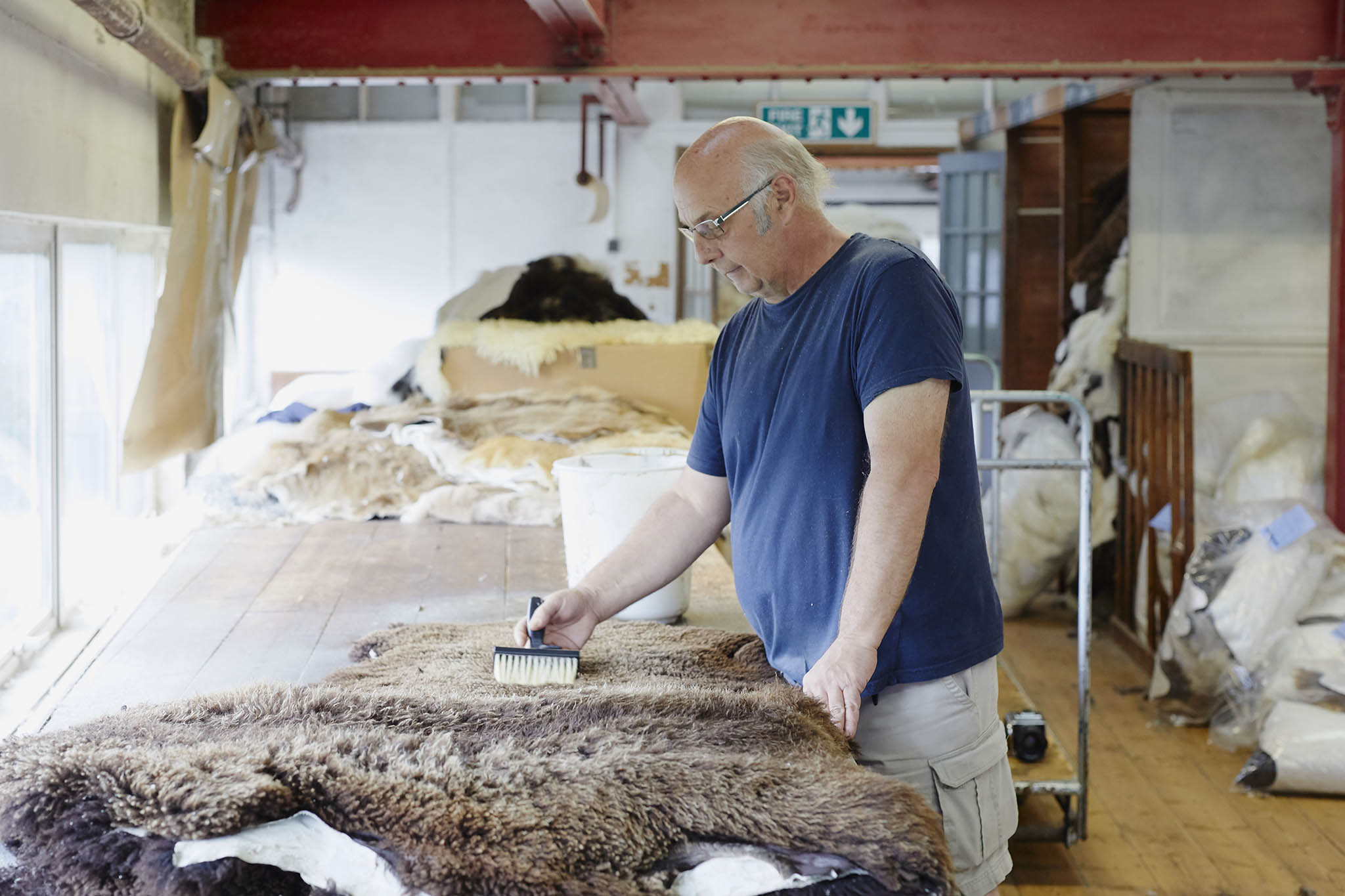 devonia worker brushing brown sheepskin at table