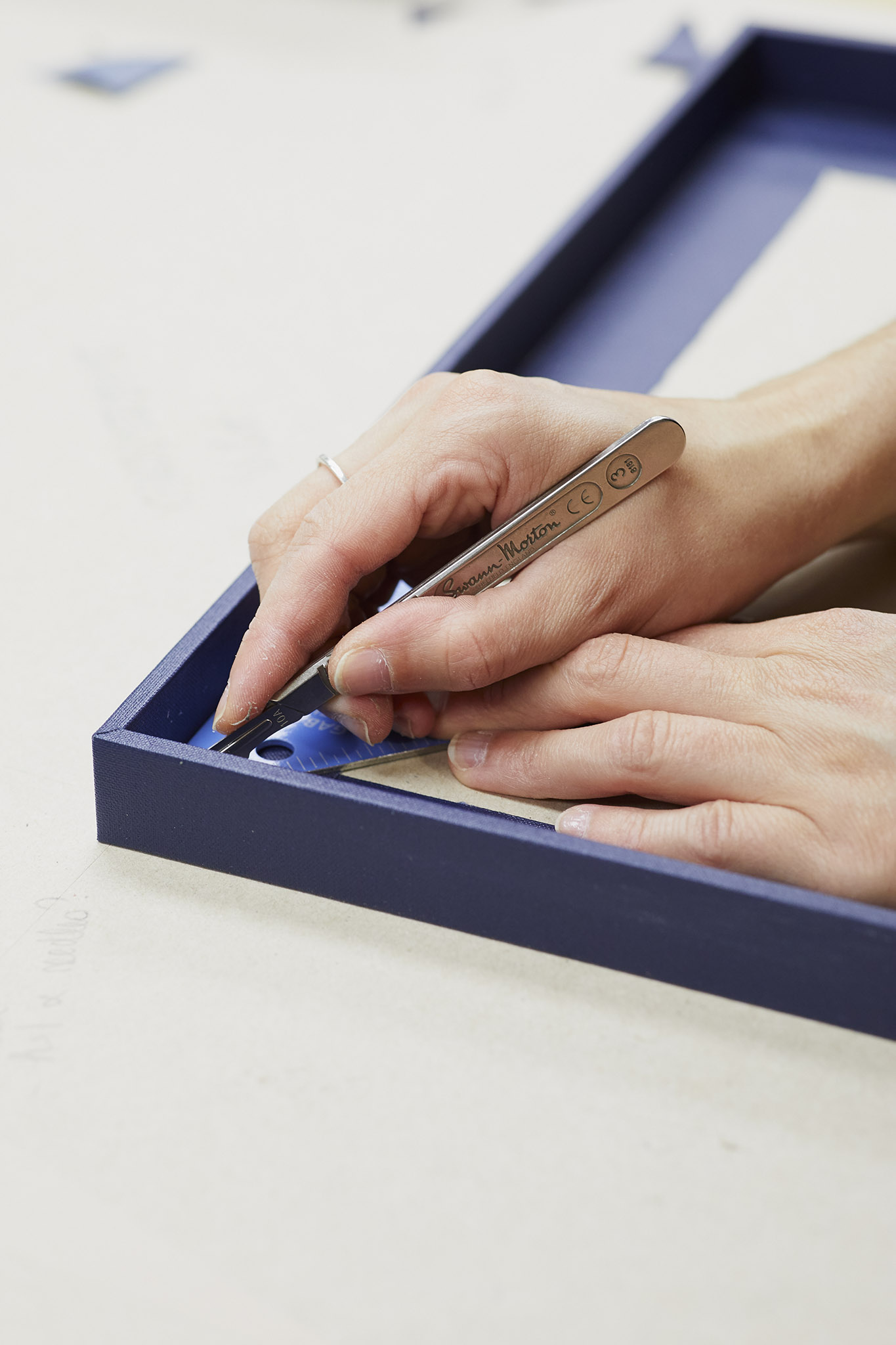 Wyvern Bindery close up of hands working on blue item