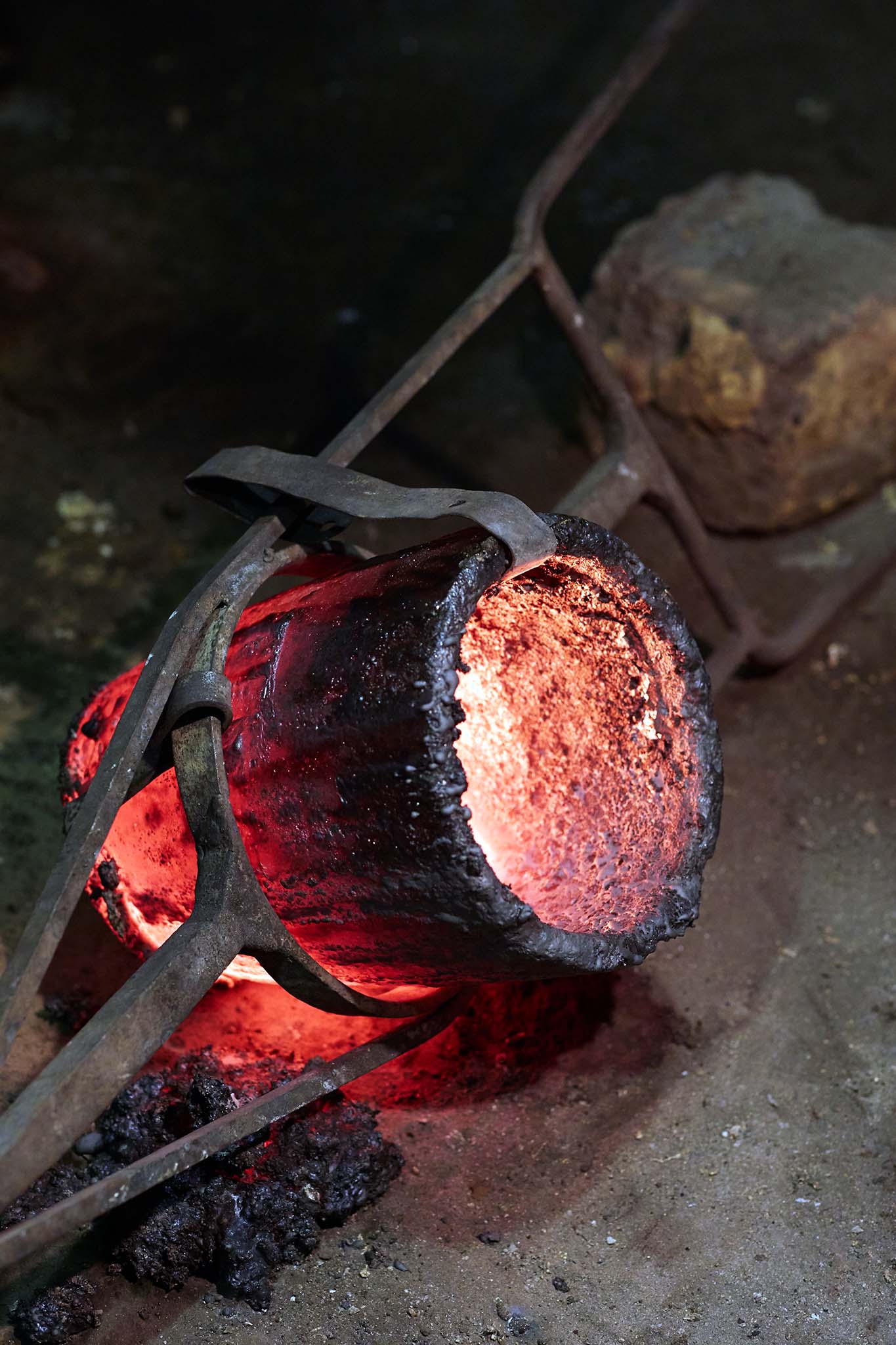 Whittons Castings glowing hot object in tongs having been removed from fire pit