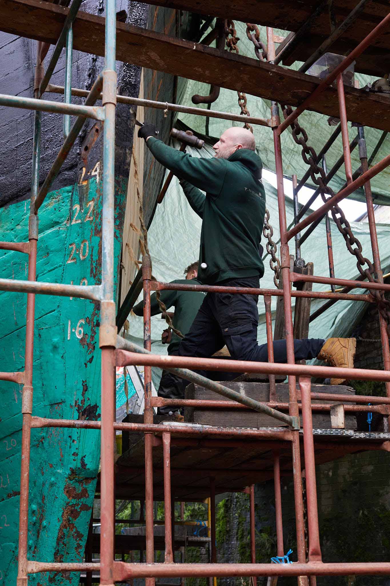 T Nielsen and Co men working high on ships hull on scaffolding 