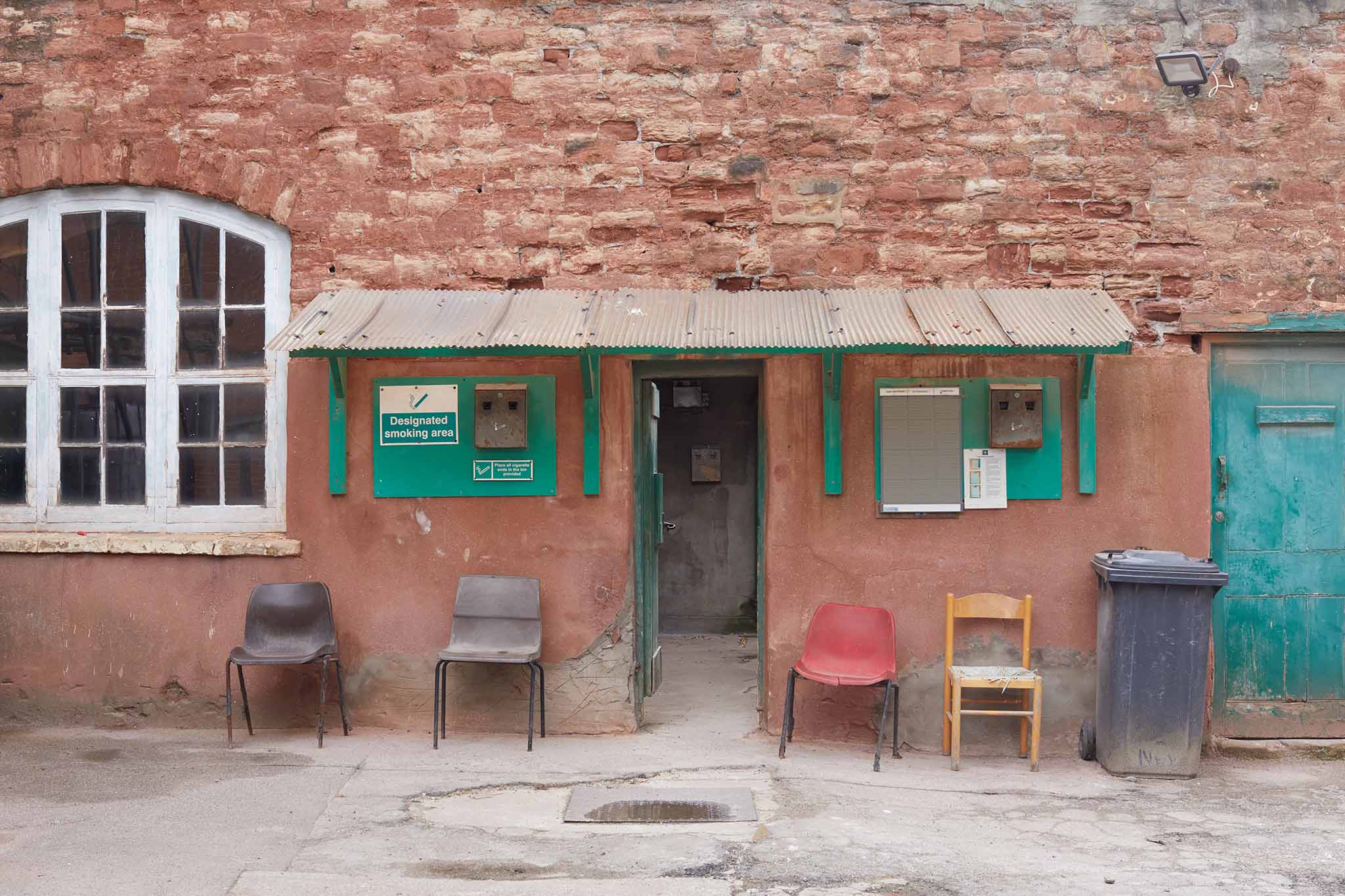 Thomas Ware and Sons outside of red brick factory four coloured chairs either side of door green painted woodwork