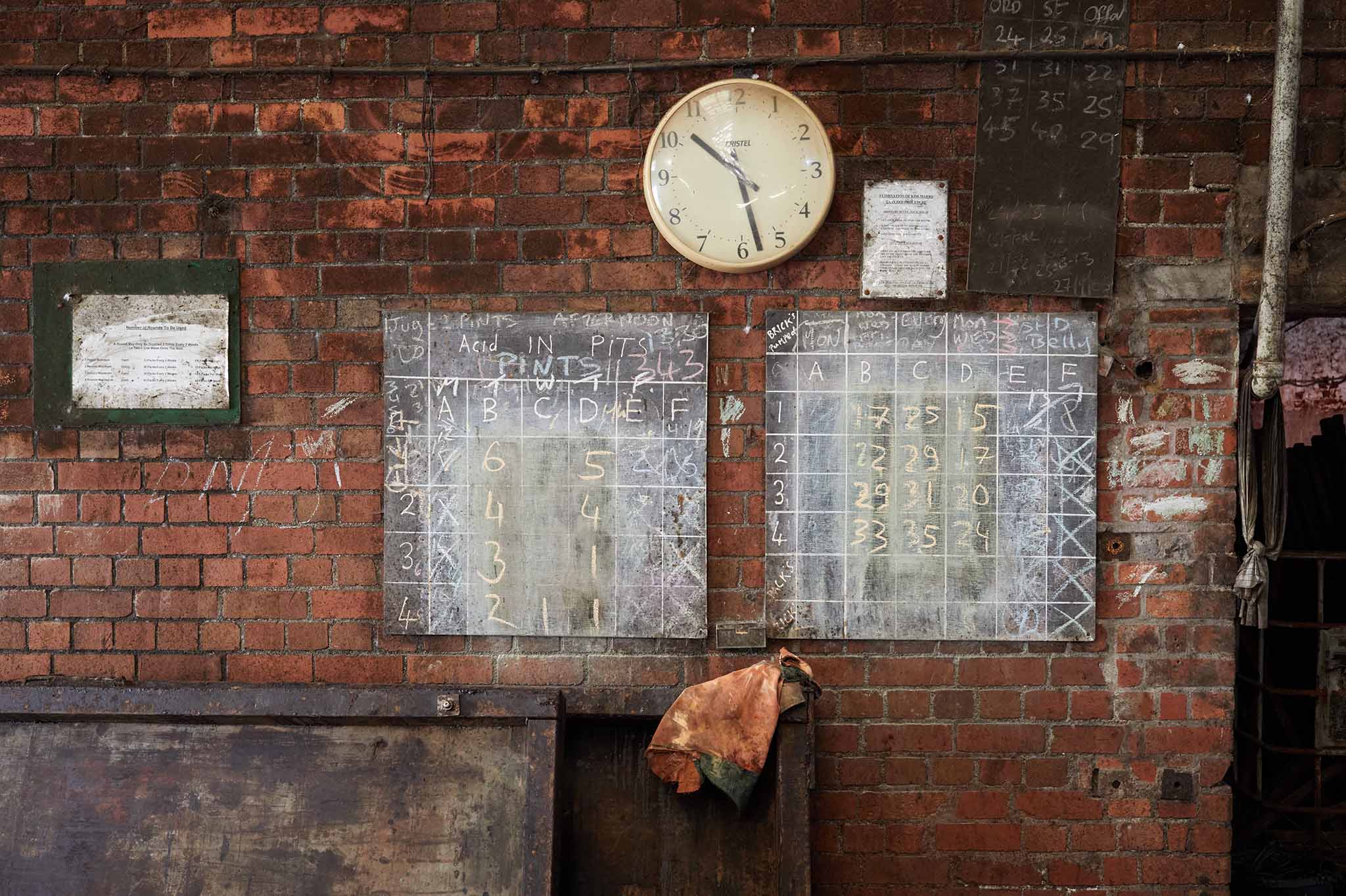 Thomas Ware and Sons clock and posters on red brick wall inside of factory