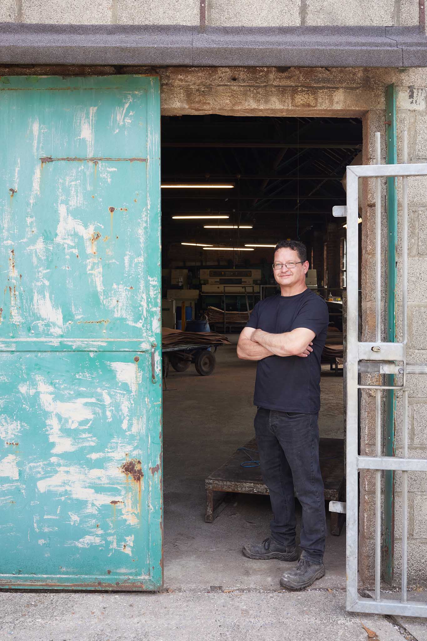 Thomas Ware and Sons worker at door of leather factory wearing black with arms crossed