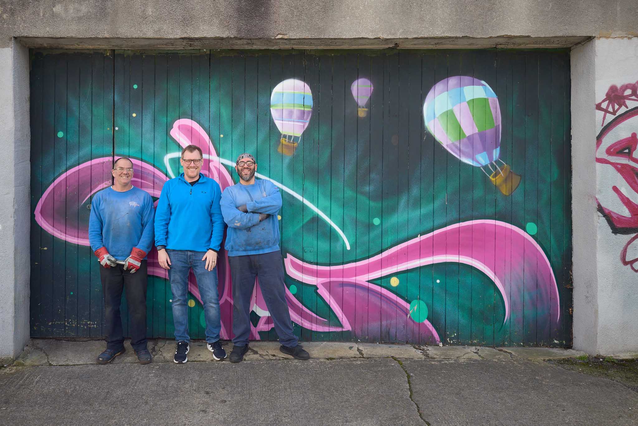 Cameron Balloons three workers in blue jackets standing in front of painted doors