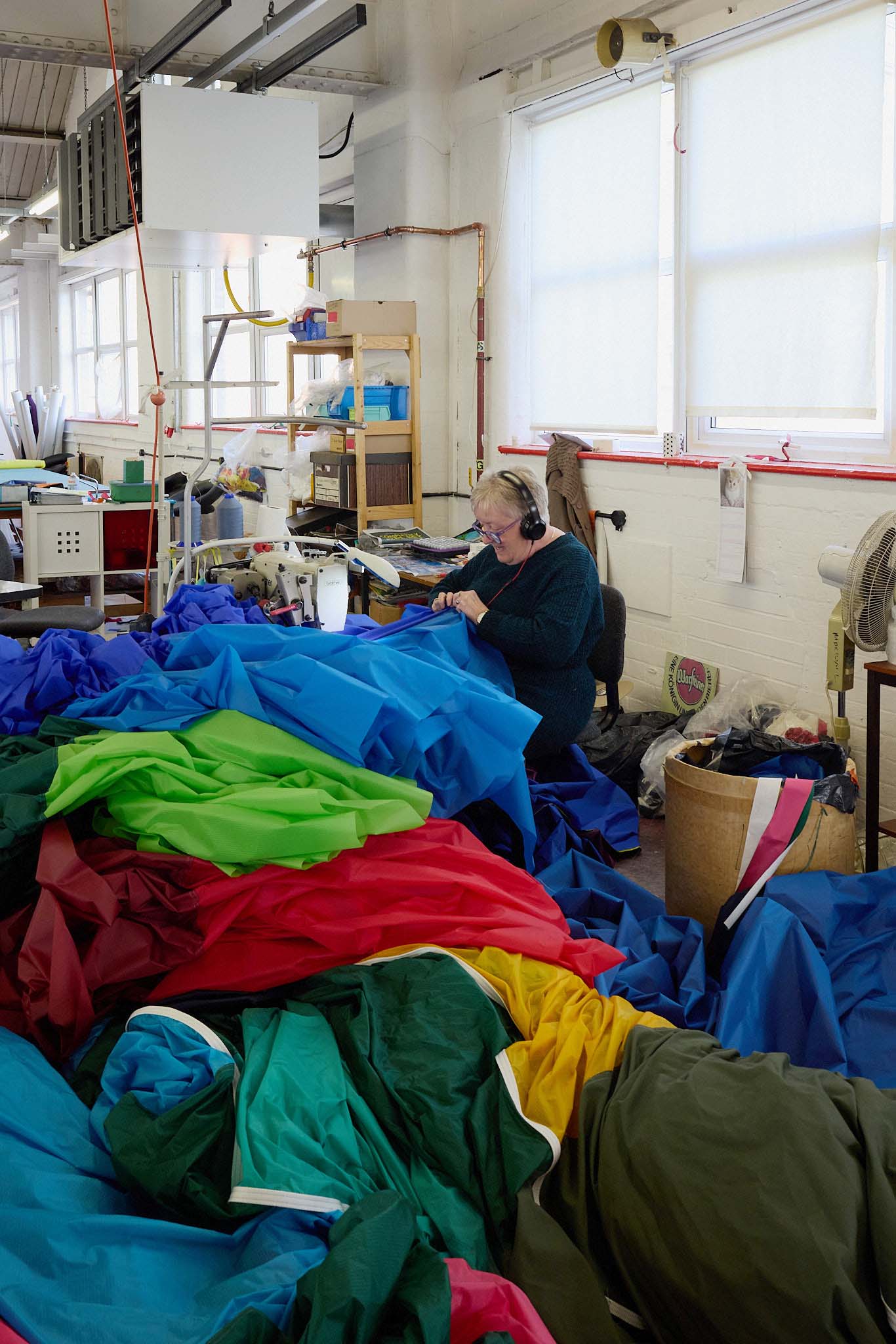 Cameron Balloons female seamstress at sewing machine in front of piles of hot air balloon fabric