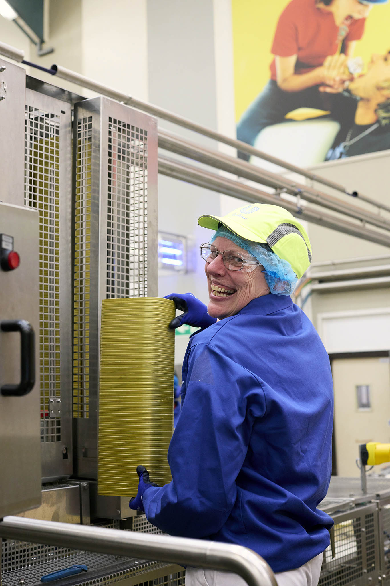 Walls Ice Cream smiling worker in blue overalls standing at factory machinery
