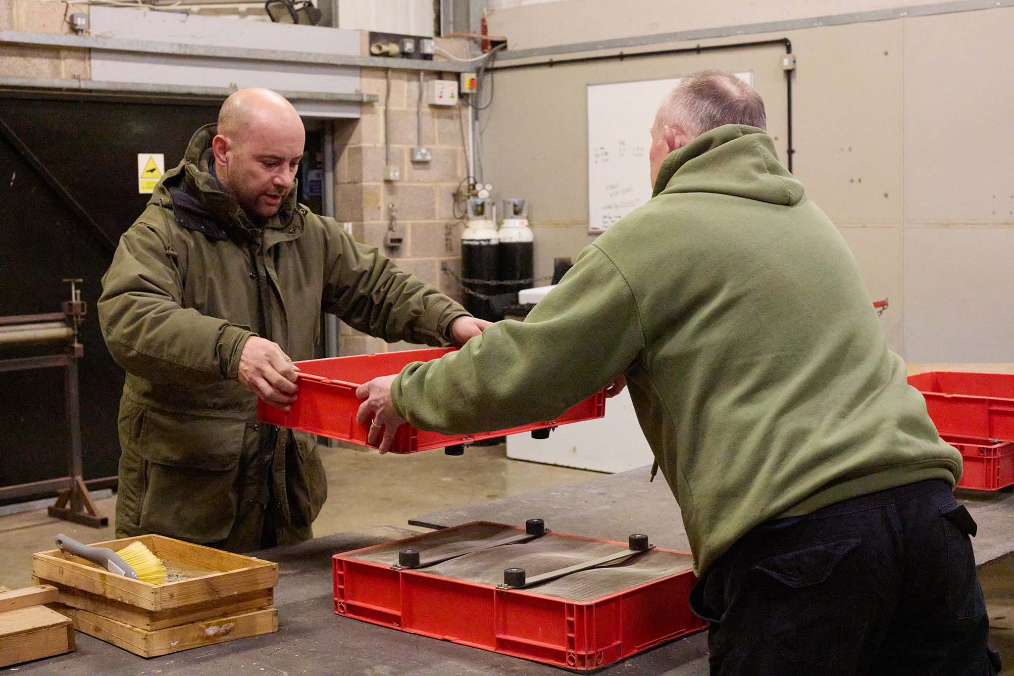 uk glass eels men inside holding orange trays of eels 