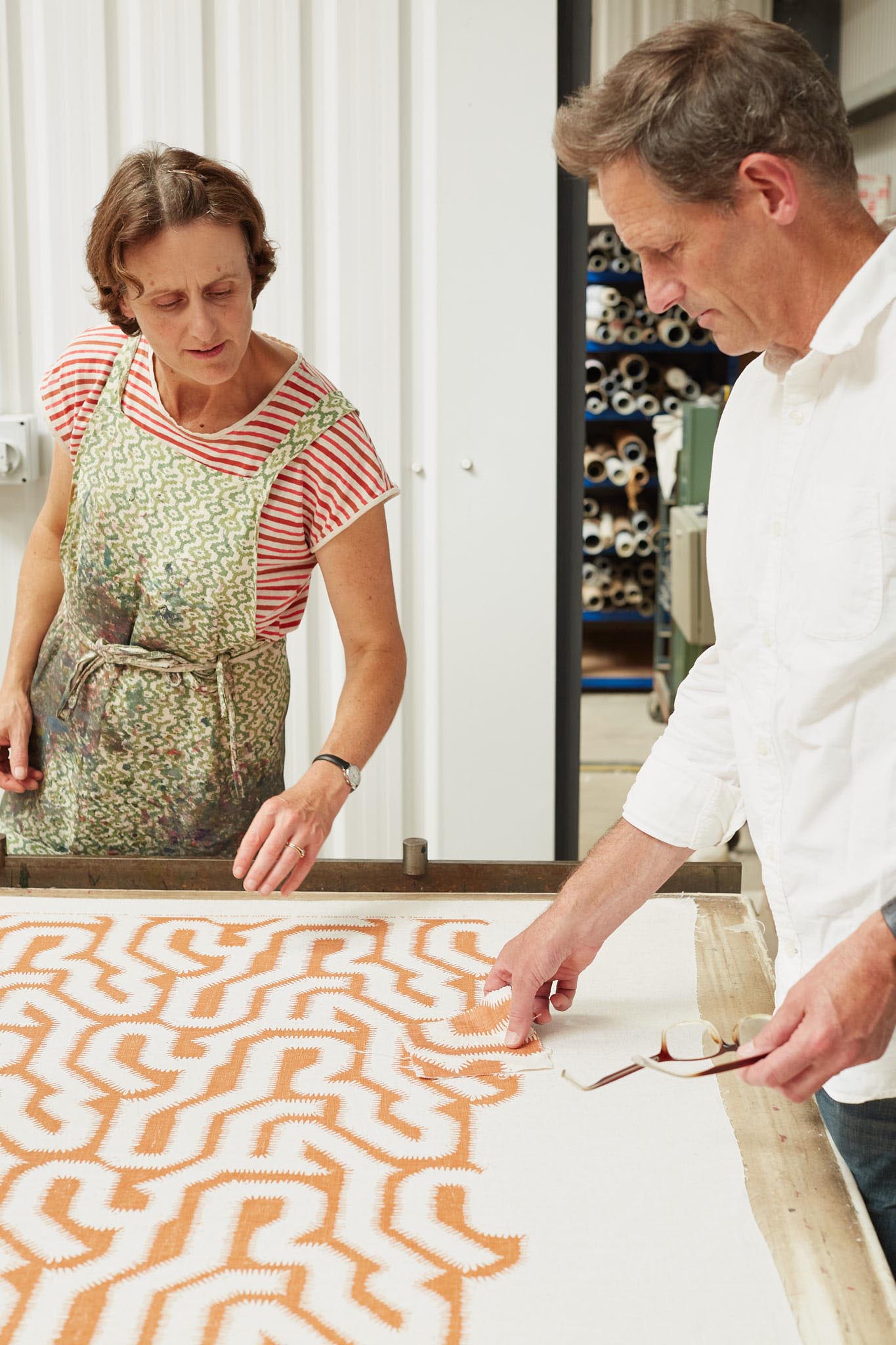 Rapture and Wright man and woman at table looking at fabric with orange design