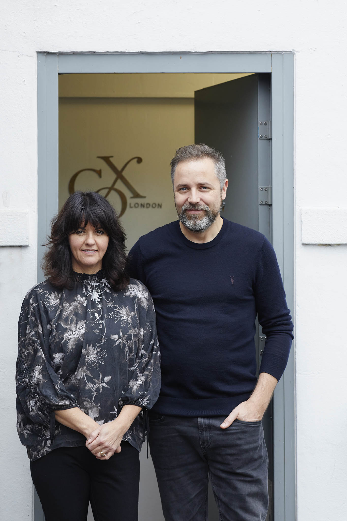 Cox London Chris and Nicola Cox man and woman standing at door of workshop