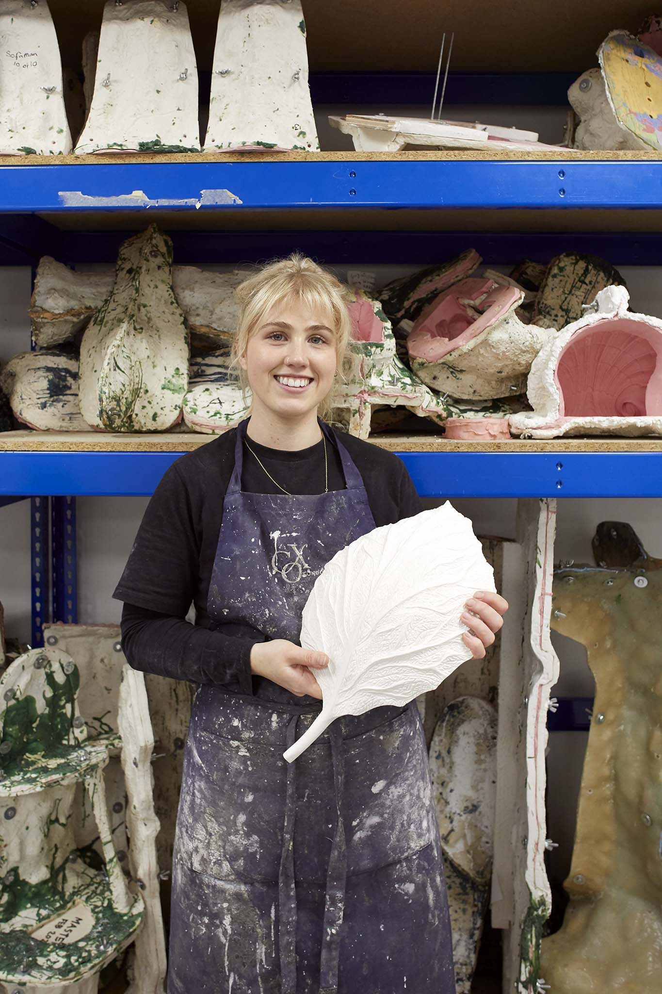 Cox London woman in blue apron standing in front of shelves she is holding large but delicate leaf