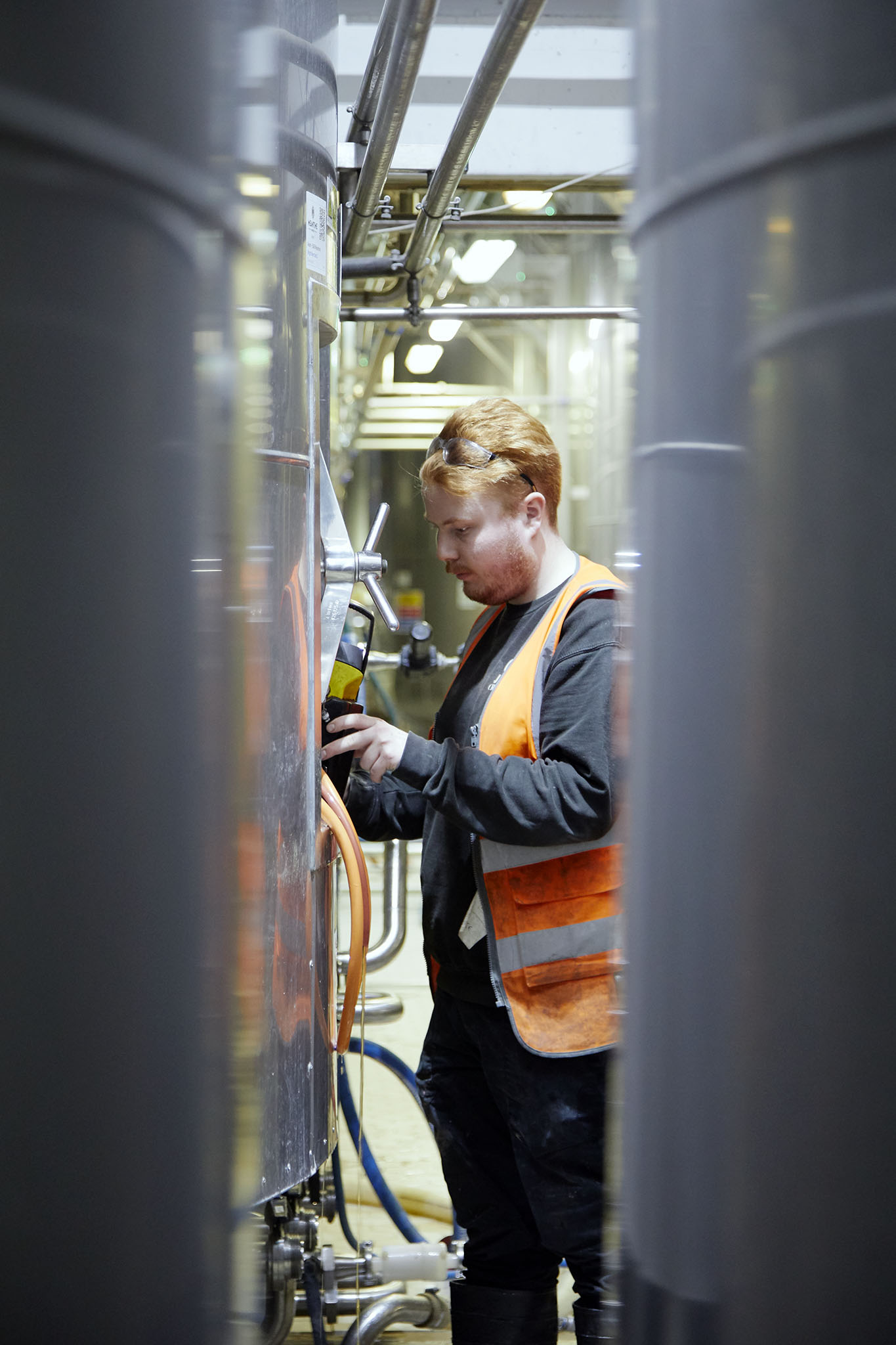 Meantime Brewing man in orange high vis next to metal silos