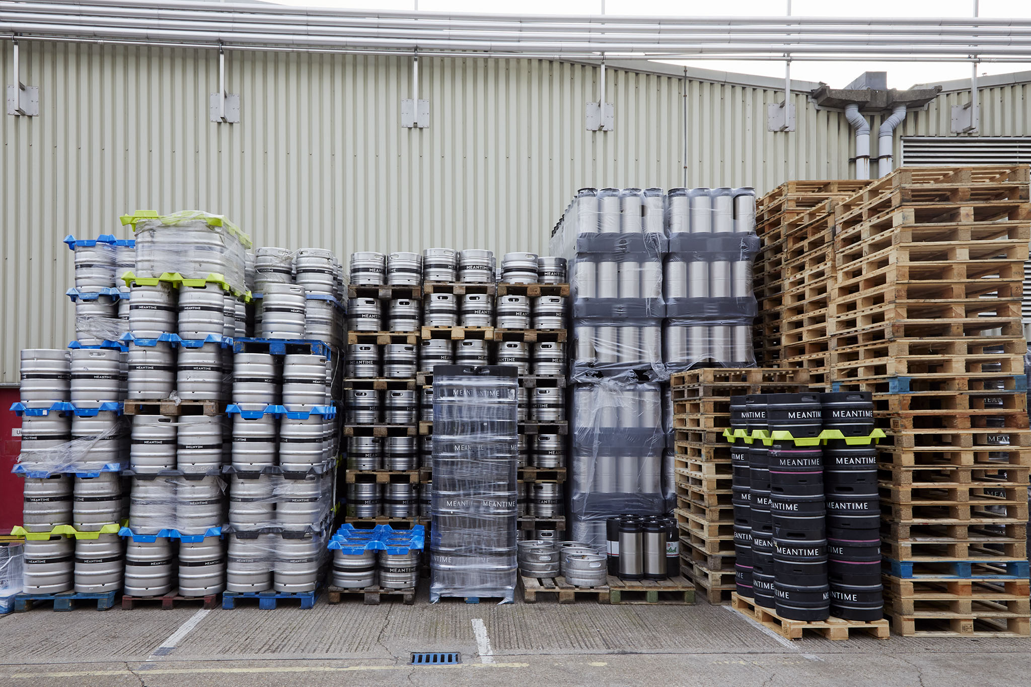 Meantime Brewing outside brewery stack of silver barrels black barrels and wooden pallets to the right