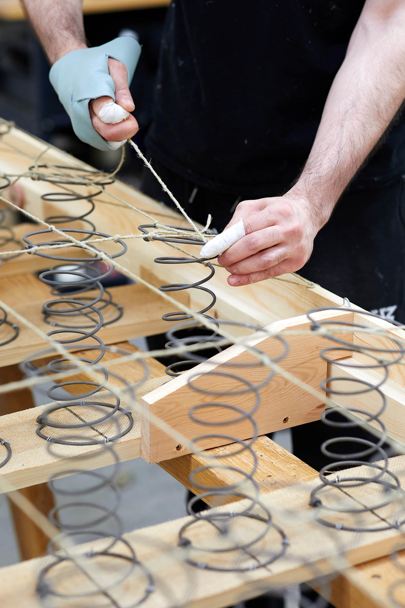 Savoir Beds close up image of employees hands black metal springs attached to wooden frame