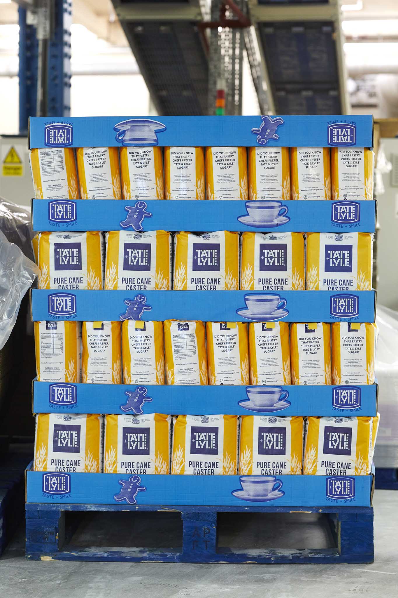 Tate and Lyle Sugars blue pallet with stacks of yellow and white packets of sugar