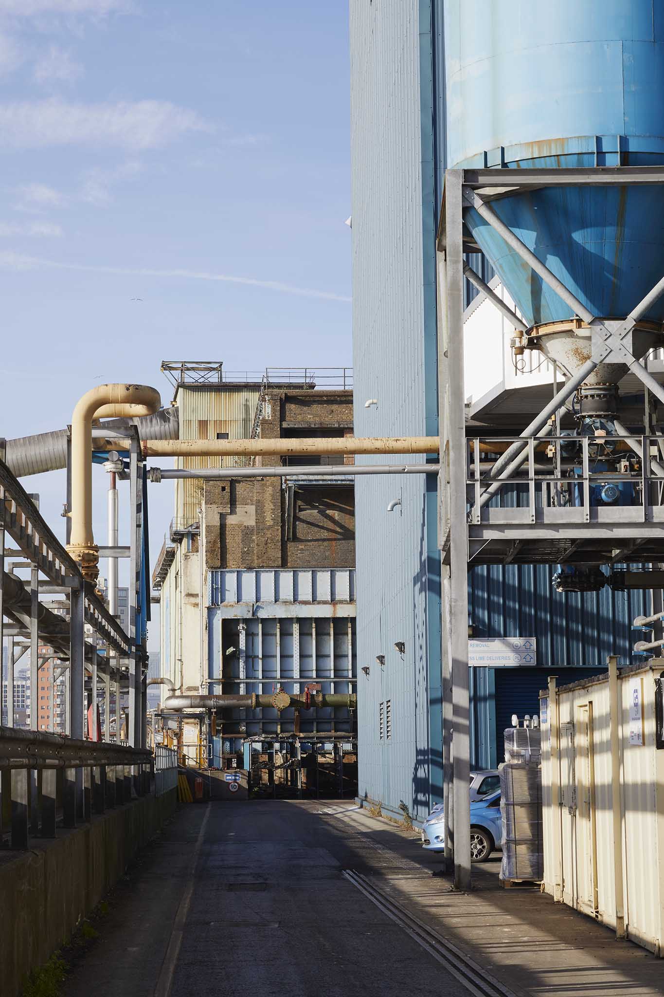 Tate and Lyle Sugars outside of refinery large blue silo to the left of image yellow piping and factory building in the background