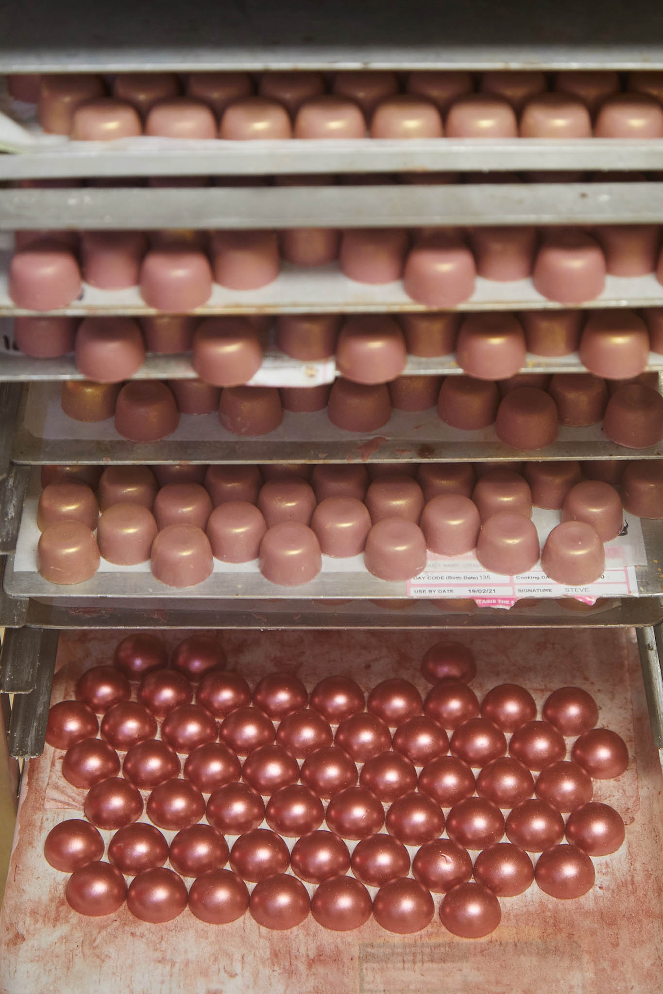 prestat trays and shelves of shiny rose gold chocolate balls