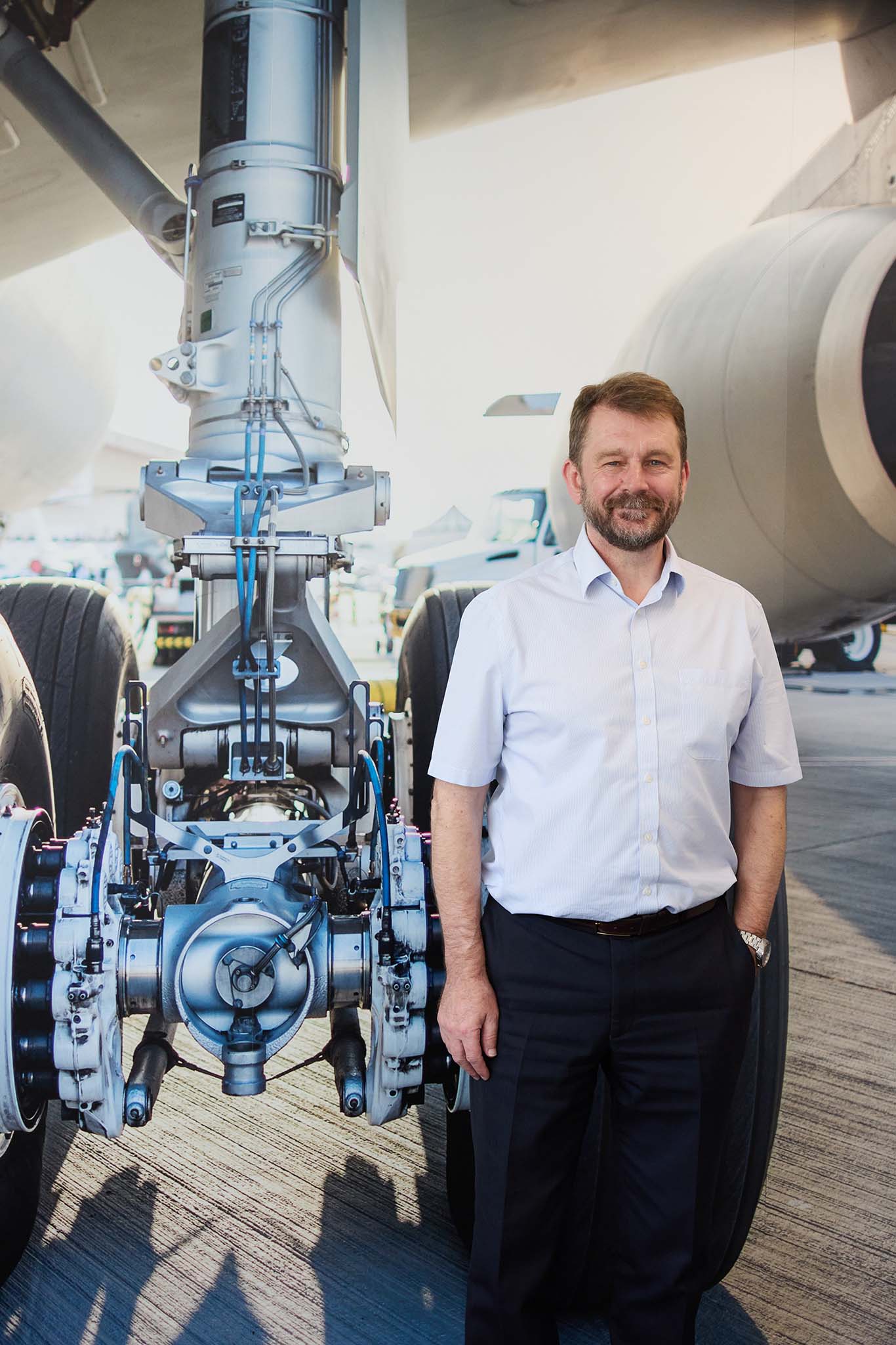 Safran Landing Systems man in white shirt and hand in pocket standing in front of aircraft landing gear large tyre
