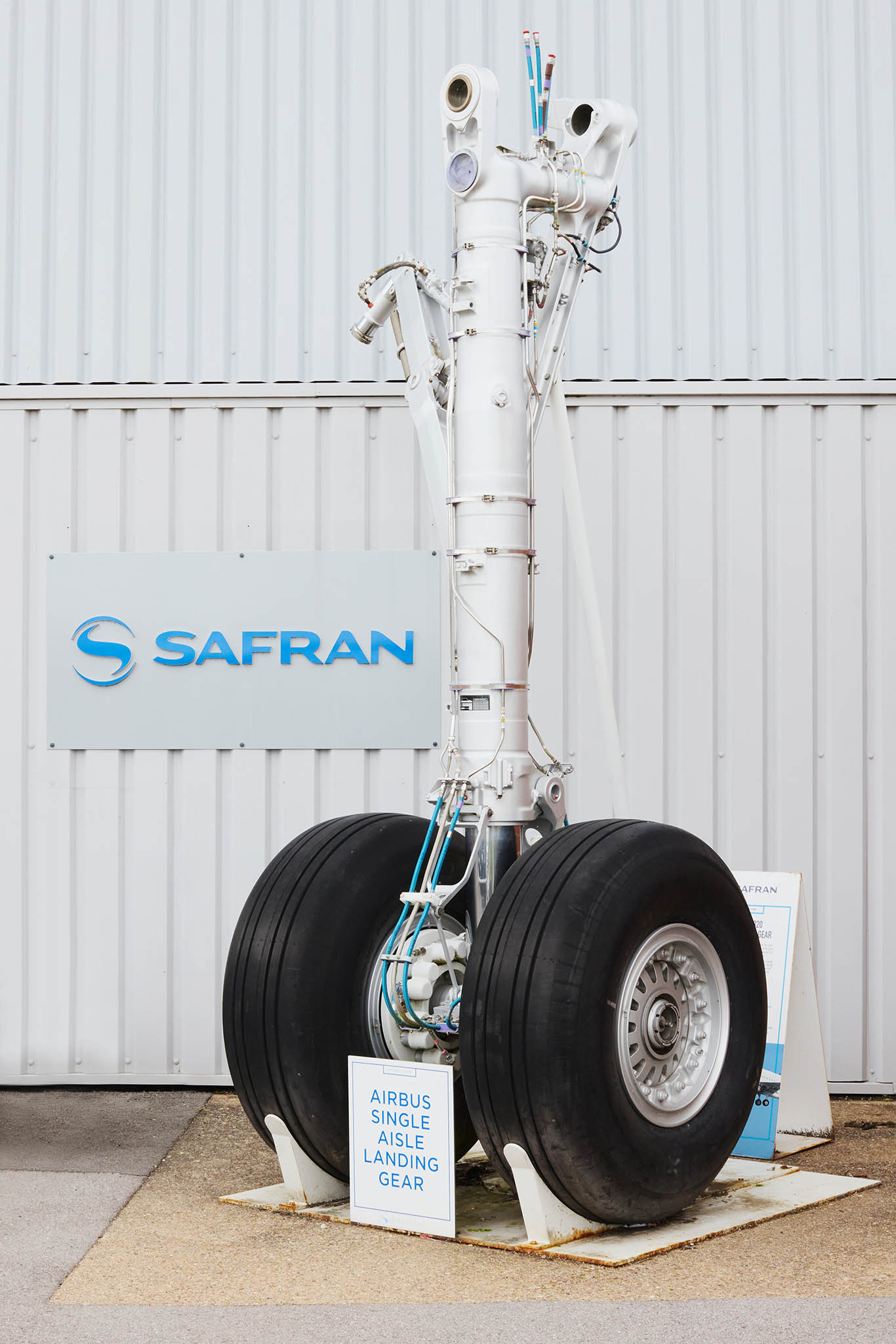 Safran Landing Systems white corrugated wall with aircraft landing gear in front two large black tyres