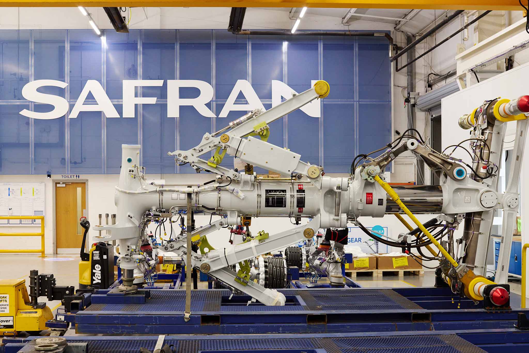 Safran Landing Systems large machine blue metal yellow with large blue sign on factory wall in background