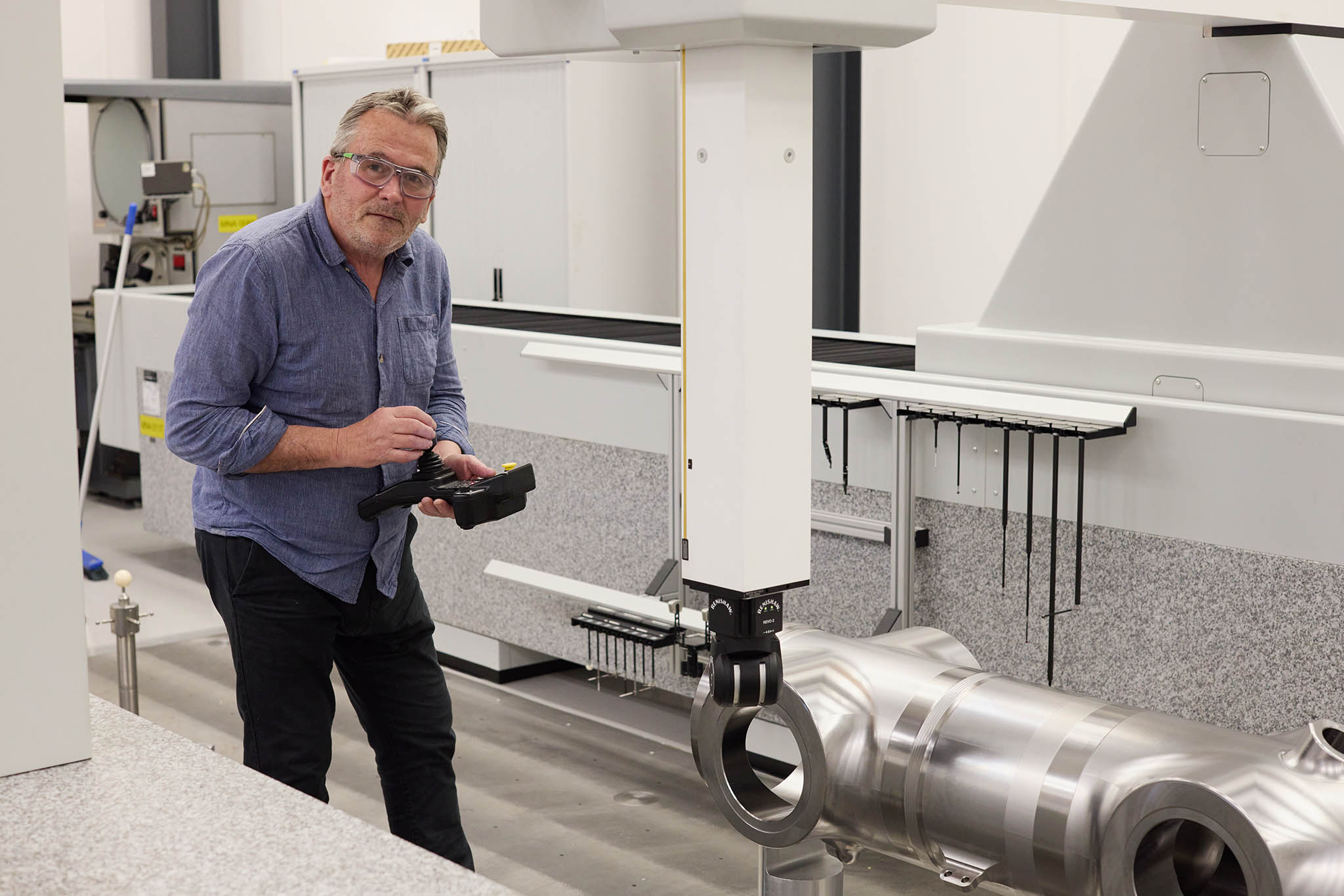 Safran Landing Systems engineer employee in blue shirt holding camera standing in white room 