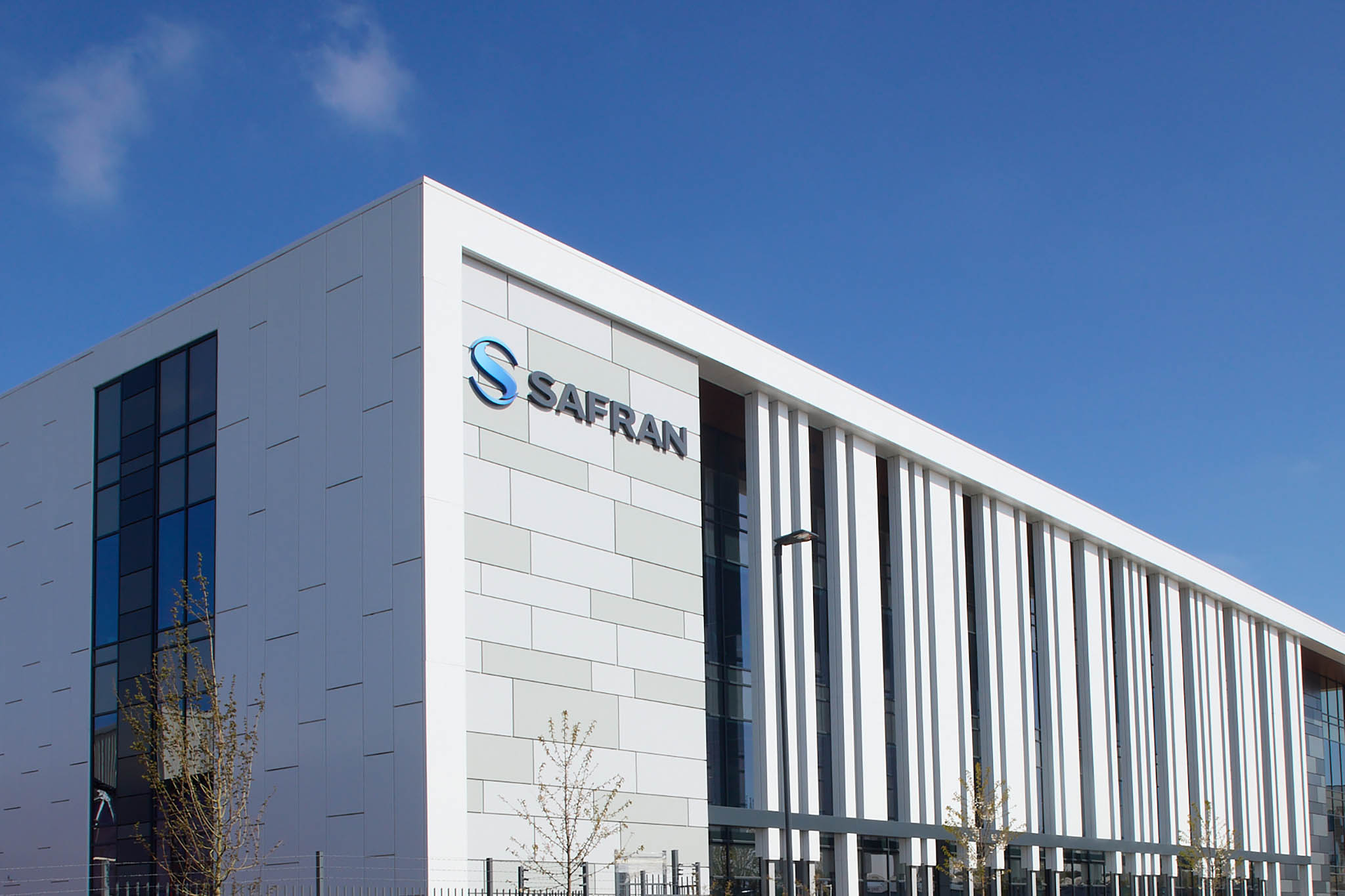 Safran Landing Systems outside of large white factory building the sky is bright blue behind