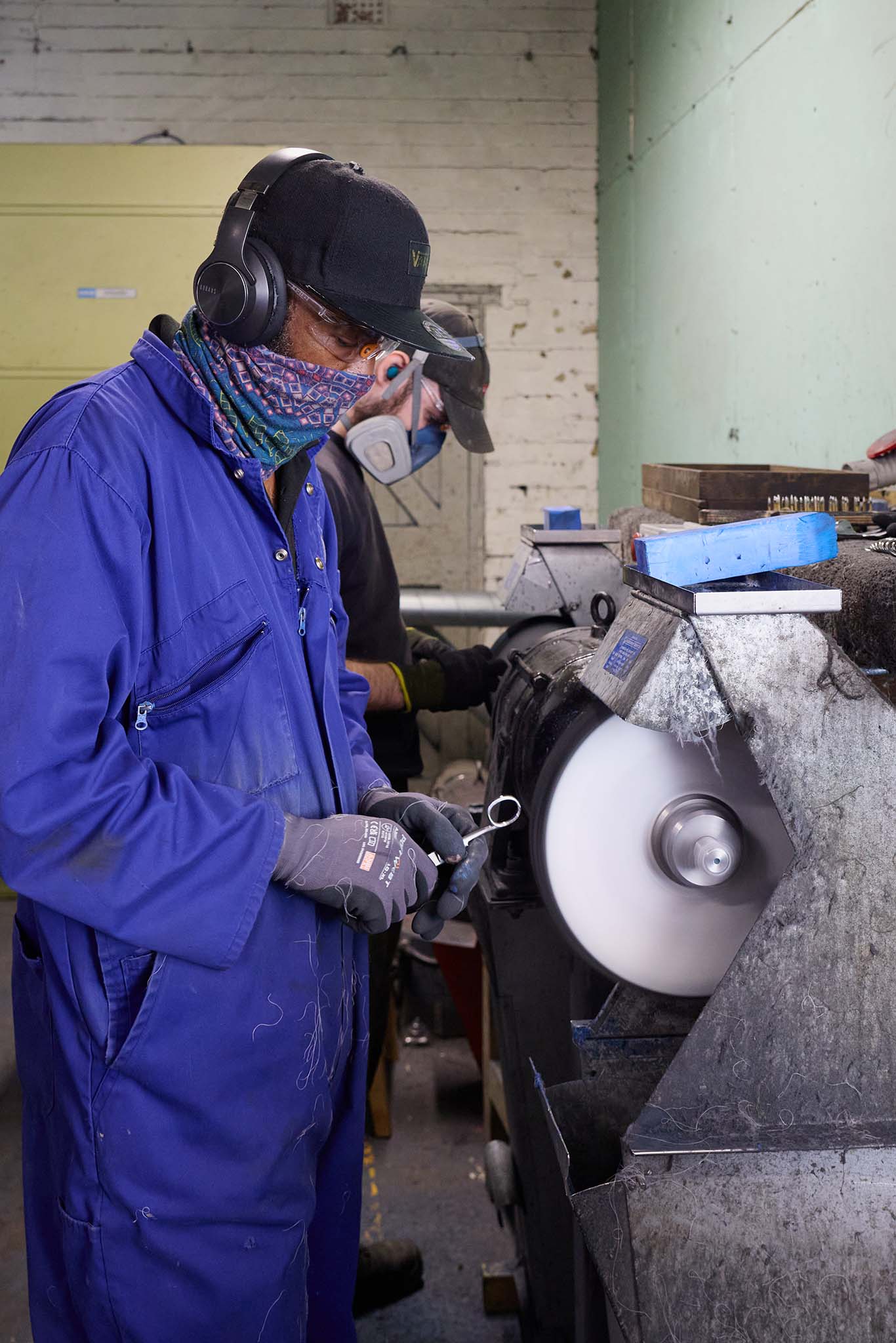 Ernest Wright man protective blue overalls and ear defenders standing at grinding wheel