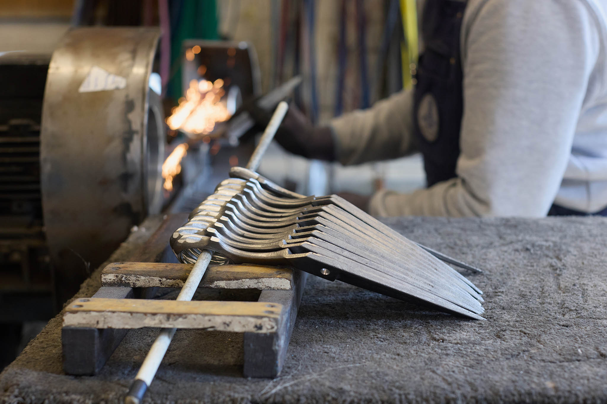 Ernest Wright row of scissor blades lined up on table looped through pole we can see putter worker in background 