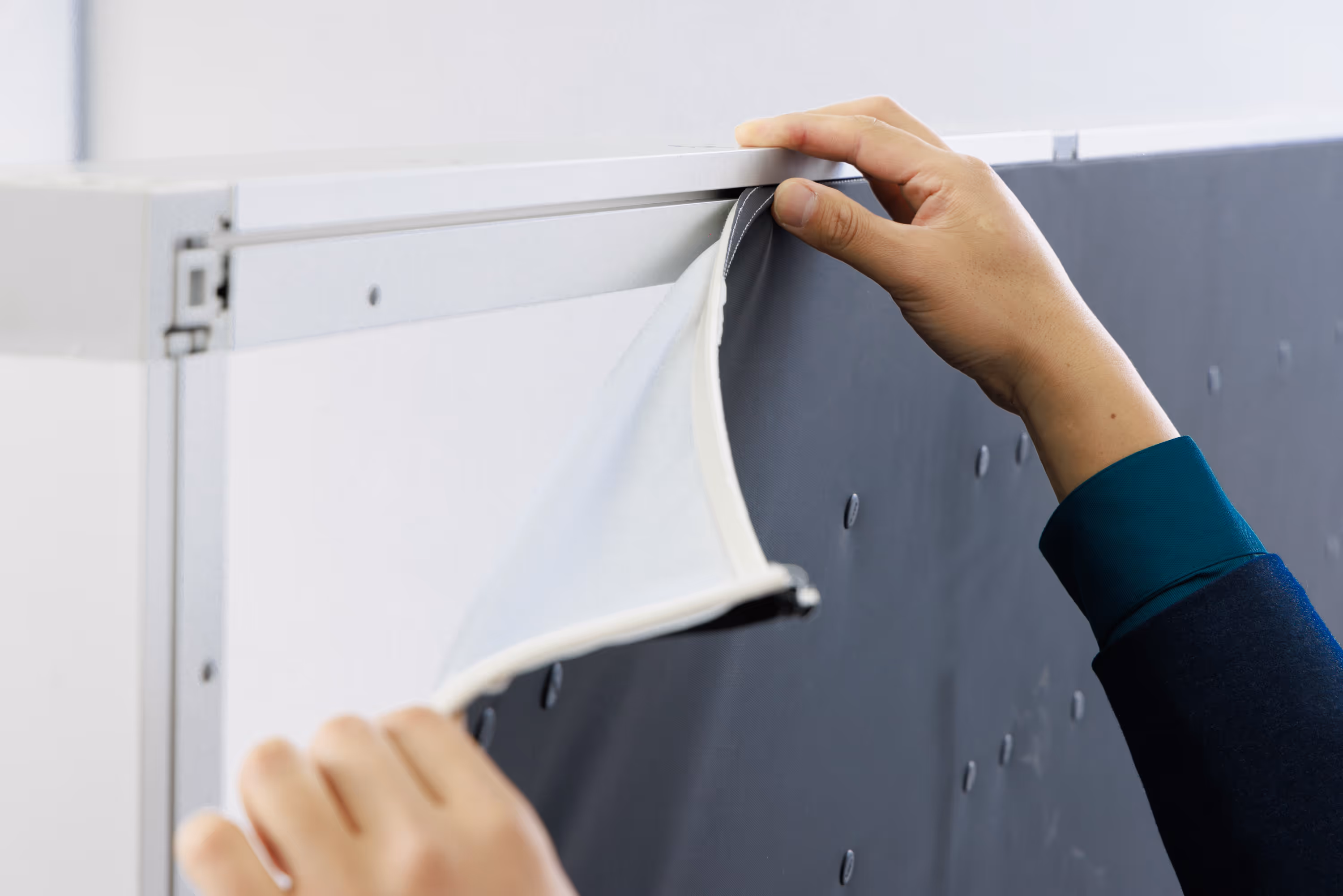 Hand peeling back a black fabric panel with LED lights attached to a backlit section.