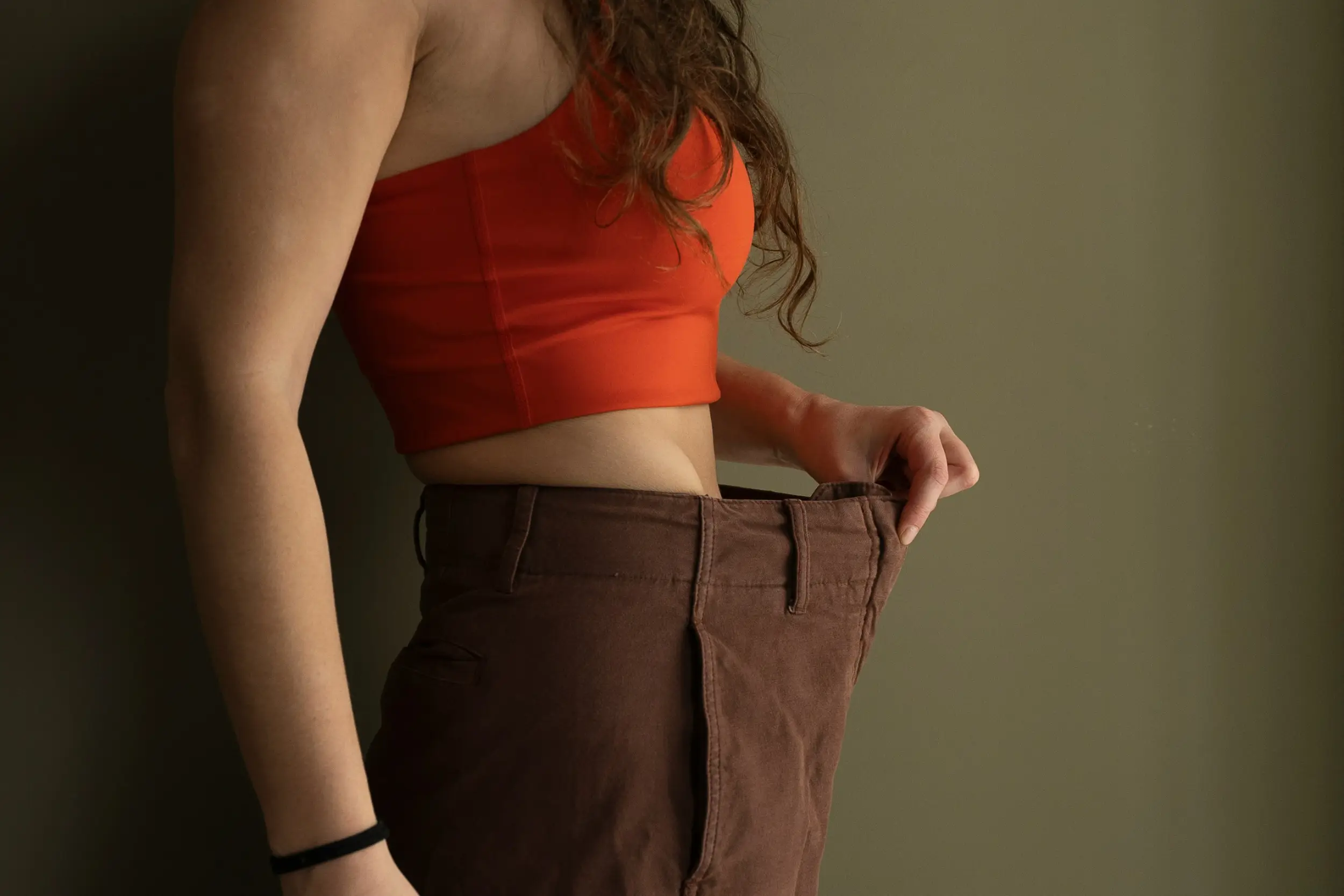 vrouw die is afgevallen en haar gewichtsverlies laat zien