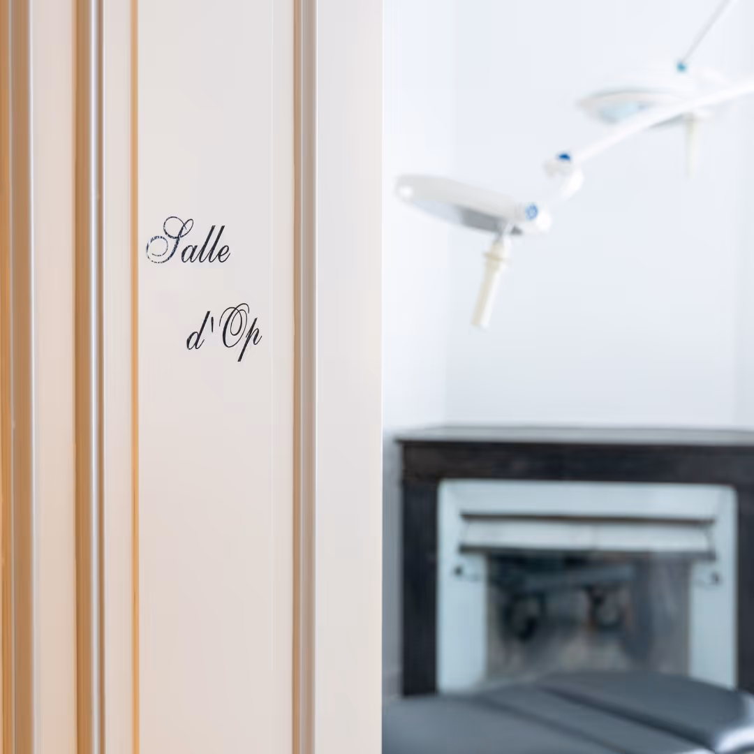 Porte beige avec inscription "Salle d'Op" menant à une salle d'opération médicale avec lampe chirurgicale et table d'examen.