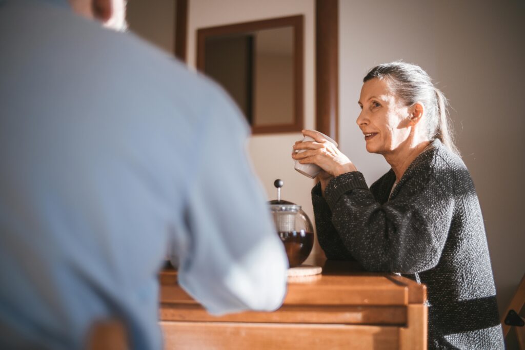 A woman and man sitting at a table with a woman drinking coffee.