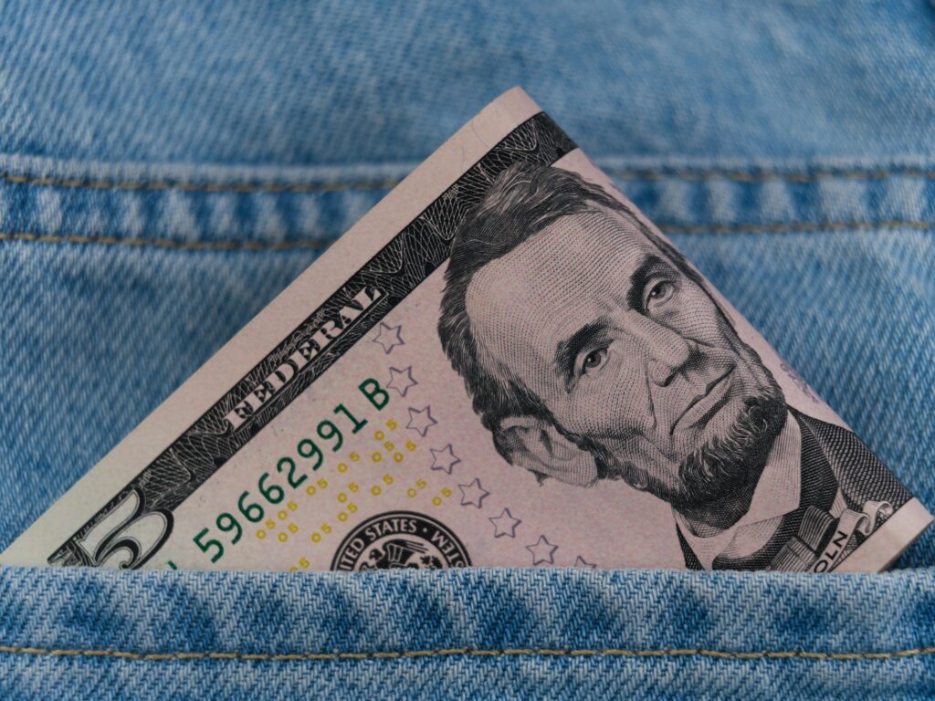A five-dollar bill in a jeans pocket representing infaltion.