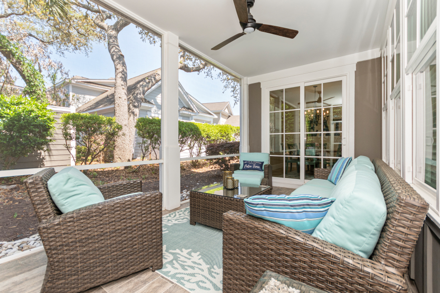 Covered patio with wicker outdoor seating, blue cushions, ceiling fan, and garden views at a North Myrtle Beach vacation rental.