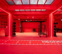 Salle de sport moderne entièrement rouge avec équipement de musculation, tapis de course et murs éclairés au néon.