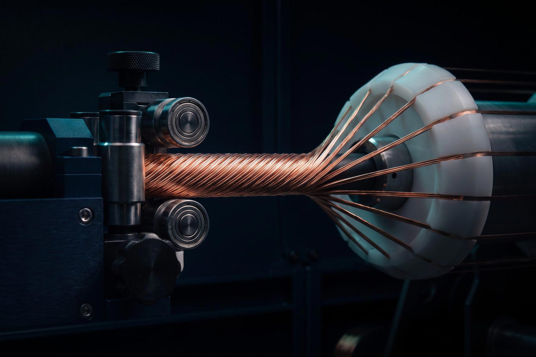 Copper wire strands being twisted into a cable on a VEIR stranding machine, with individual wires fanning out from a guide plate.