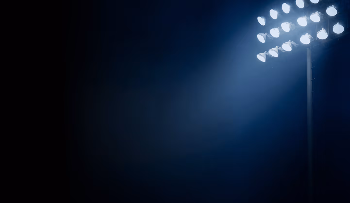Bright stadium floodlights illuminating a dark night sky.